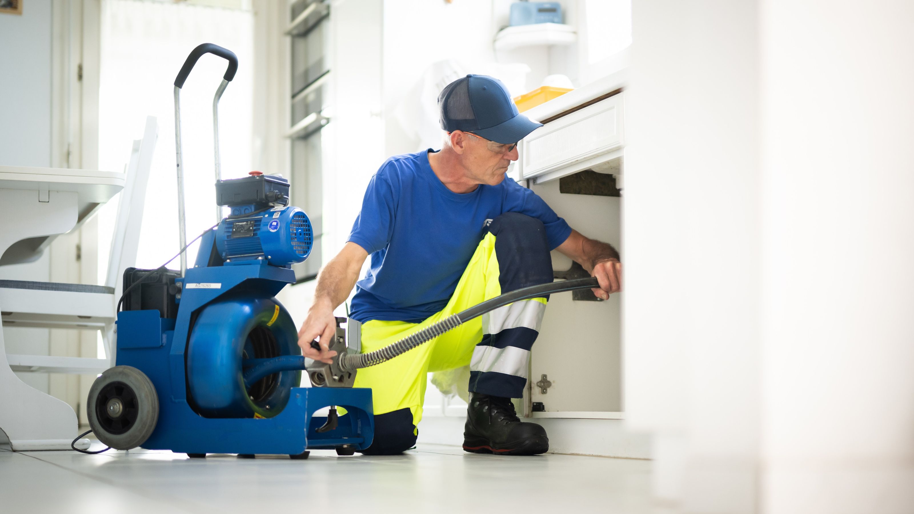 Mitarbeiter der iTS reinigt eine Leitung in einer Küche mit der Rohrreinigungsmaschine